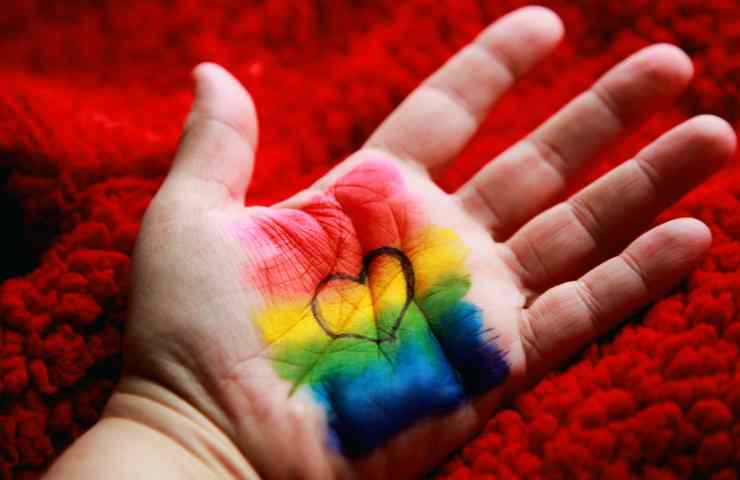 Foto di una mano con disegnato un arcobaleno