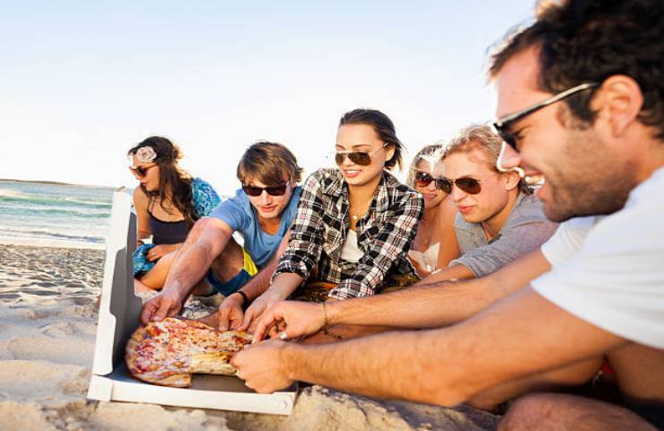 Gruppo di ragazzi con una pizza al mare