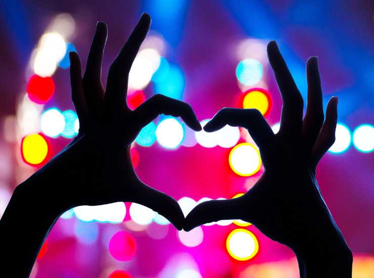 Un cuore con le mani su sfondo a luci di un concerto