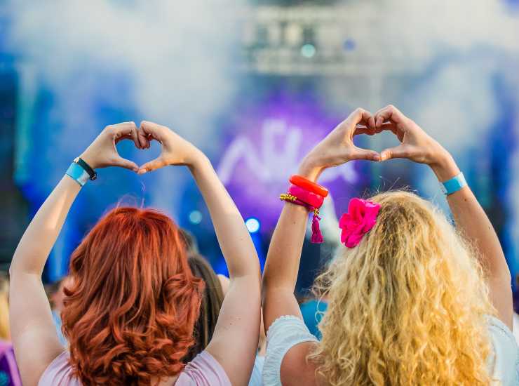 Due ragazze creano un cuore con le mani durante un concerto