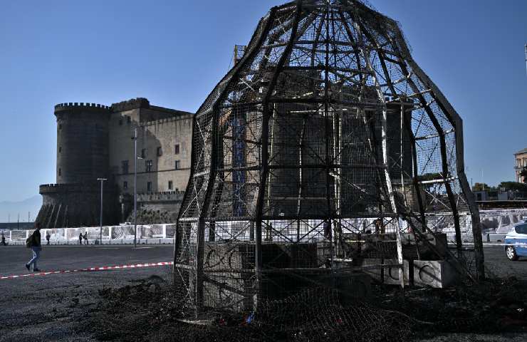 Struttura della Venere presa a Fuoro tutta annerita dalle fiamme e dal fumo con dietro un castello di Napoli