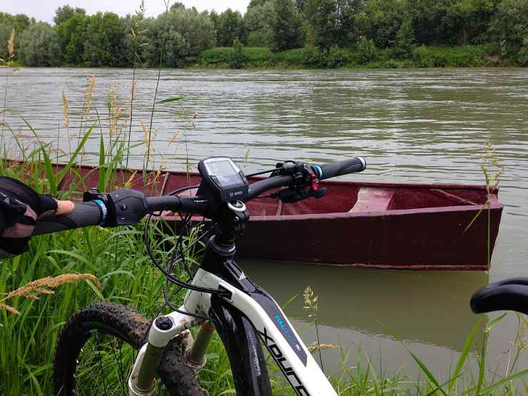 Bici elettrica sulla riva del fiume Po e canoa